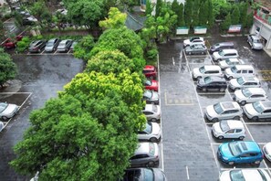 Un estacionamiento con varios autos y un árbol grande en el centro.