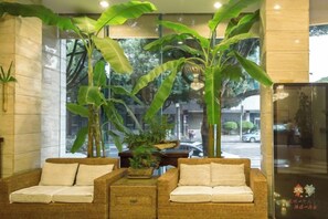A lobby with wicker furniture, large windows, and indoor plants. - Landu Business Hotel (Tengchong)