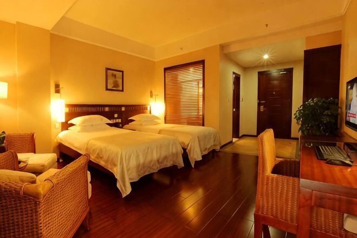 A hotel room with two beds, a desk, and a chair.