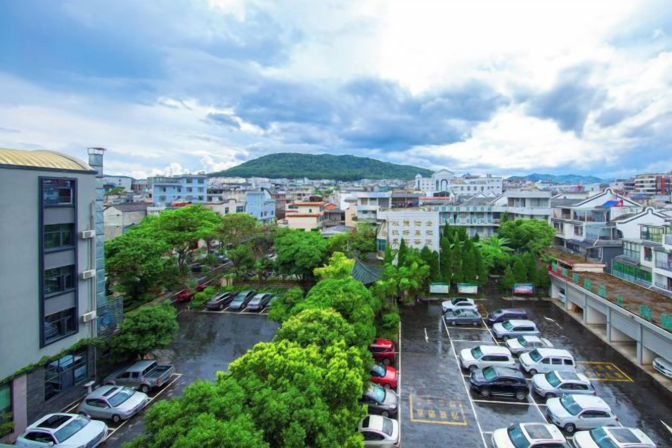 A parking lot with multiple cars, surrounded by buildings and greenery.