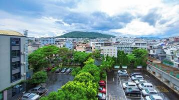 A parking lot with multiple cars, surrounded by buildings and greenery.