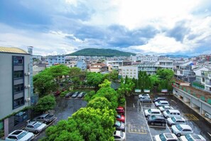 A parking lot with multiple cars, surrounded by buildings and greenery. - Landu Business Hotel (Tengchong)