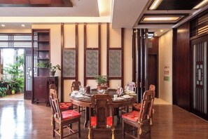 A dining area with a round table, red cushioned chairs, and a decorative wall panel. - Landu Business Hotel (Tengchong)