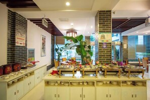 A restaurant with a brick wall, a wooden ceiling, and a buffet setup. - Landu Business Hotel (Tengchong)