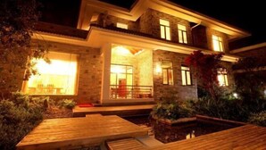 Uma casa moderna com entrada bem iluminada, área de estar coberta ao ar livre e um pequeno jardim.