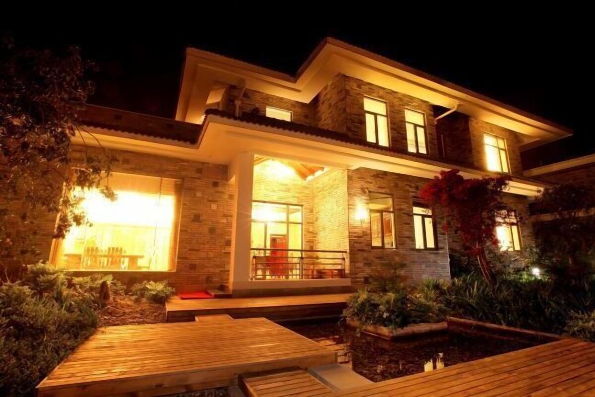 A modern house with a well-lit entrance, a covered porch, and a landscaped garden.