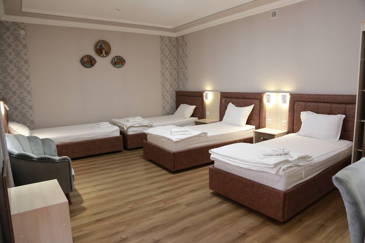 Une chambre d’hôtel avec quatre lits simples, un canapé et un bureau.