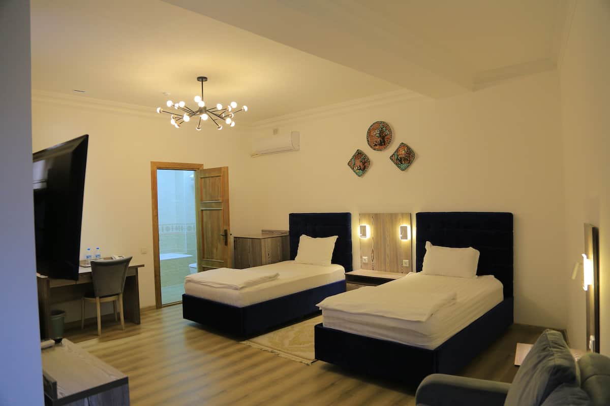 Une chambre d’hôtel avec deux lits, un bureau, une chaise, une télévision et un lustre.