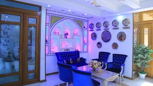 A room with a blue sofa set, a dining table, and a decorative wall with plates and a large window with a view.