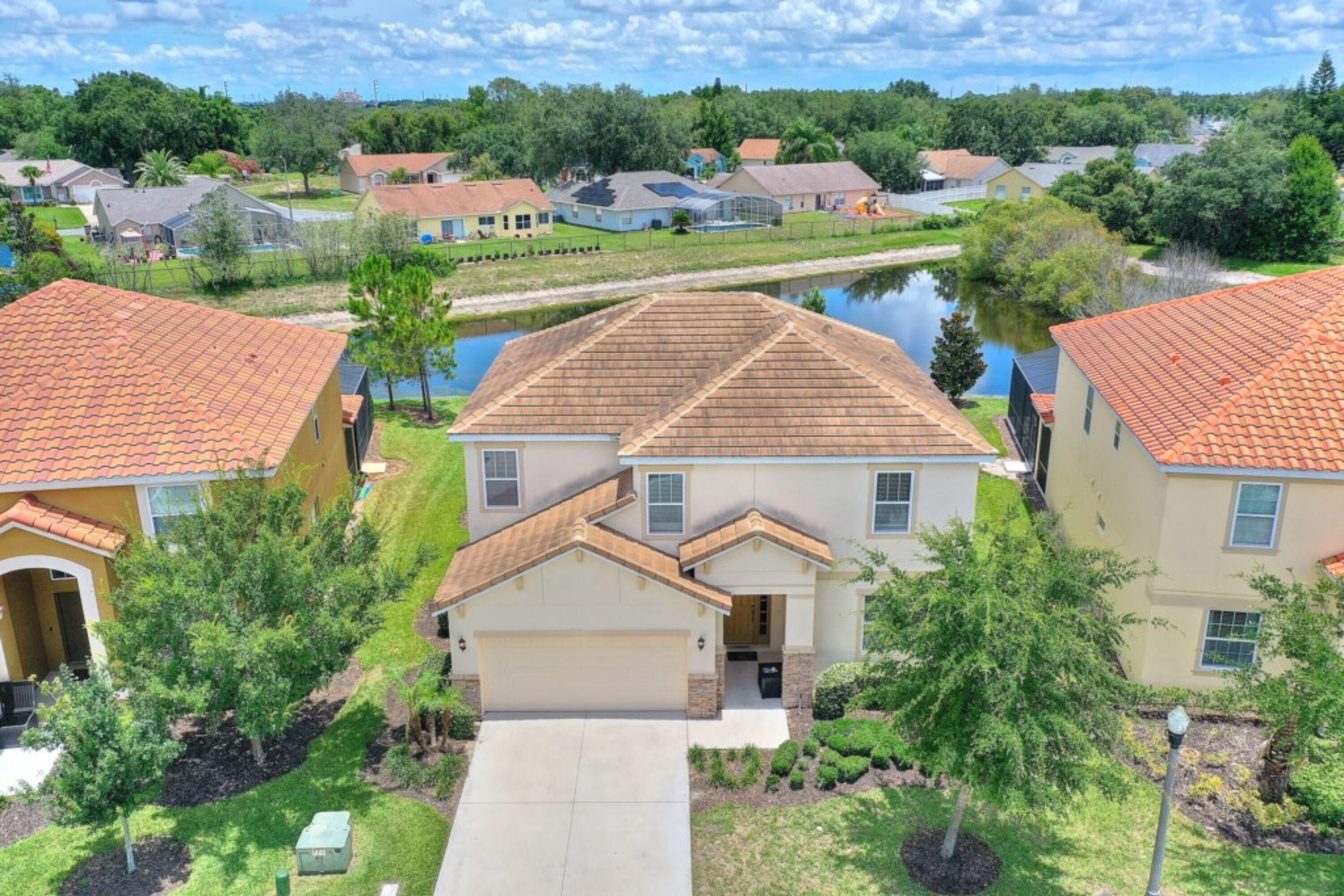 A residential area with houses featuring red-tiled roofs, a central water body, and well-maintained lawns.
