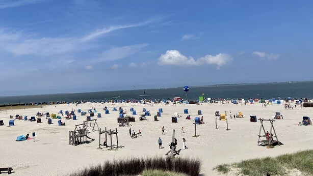A beach with numerous tents and beachgoers. - Ferienhaus in Nessmersiel, Deich- und Inselblick, Glasfaser (Dornum)