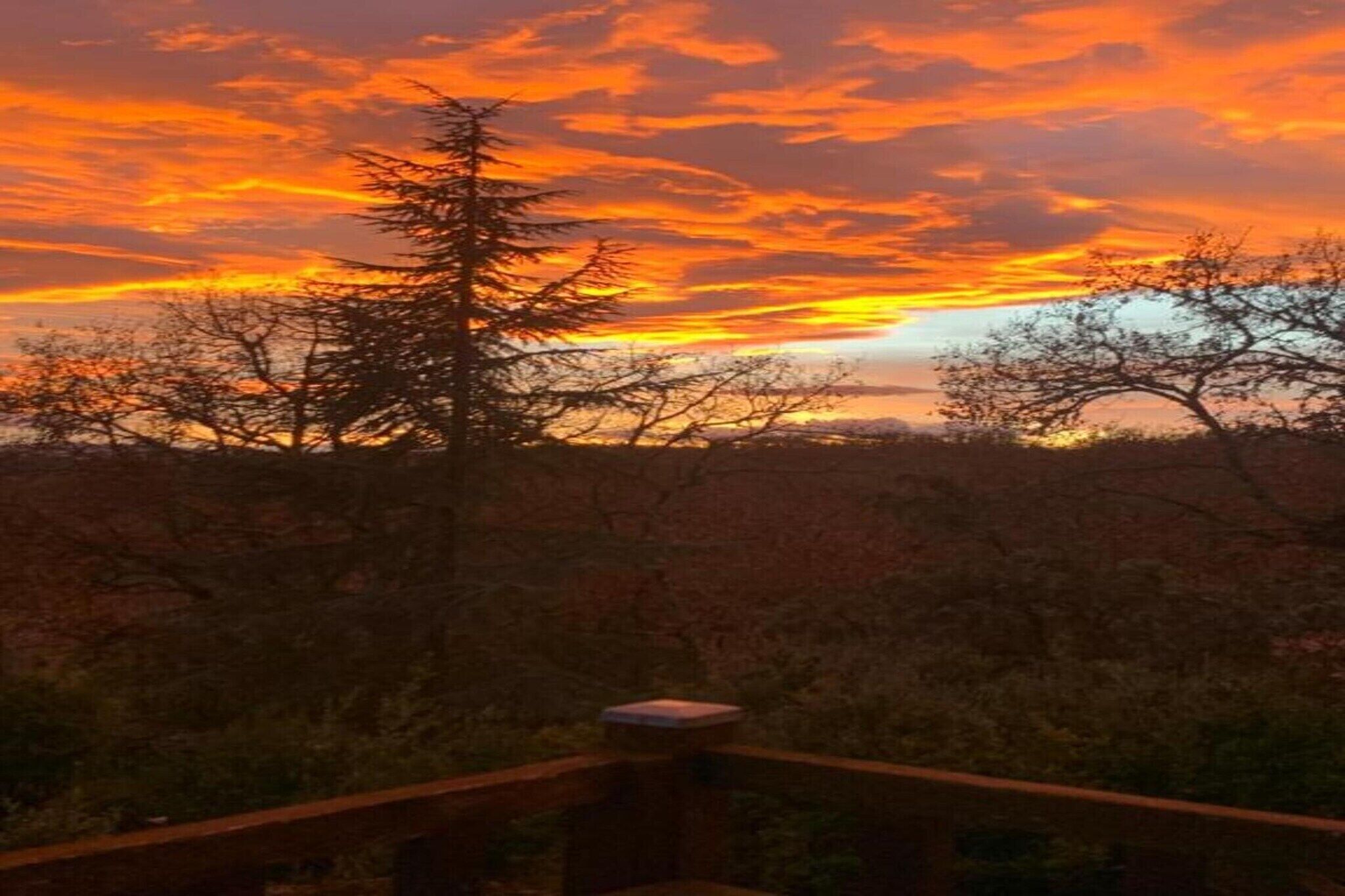 A sunset view with a wooden deck and sparse vegetation.