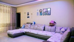 Un salon avec un canapé d’angle, une petite table et un mur orné de tableaux.