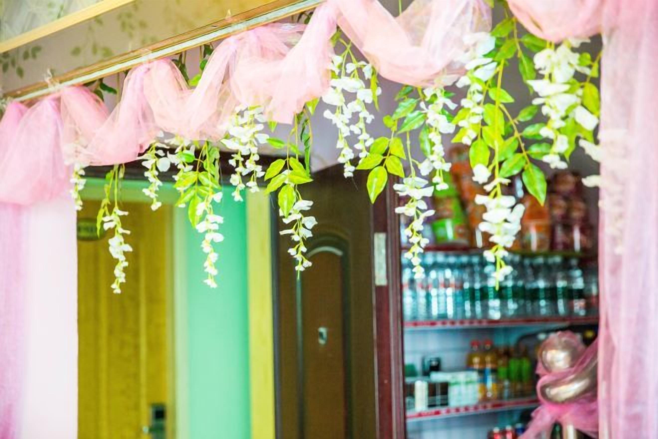 A doorway with hanging white flowers and pink fabric.