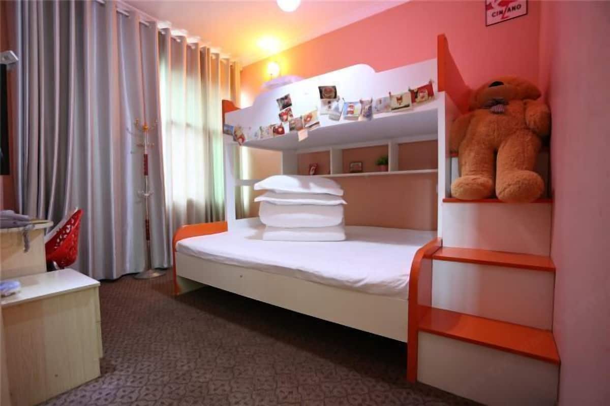 Una habitación con una cama litera, un escritorio pequeño y un oso de peluche grande en la cama superior.