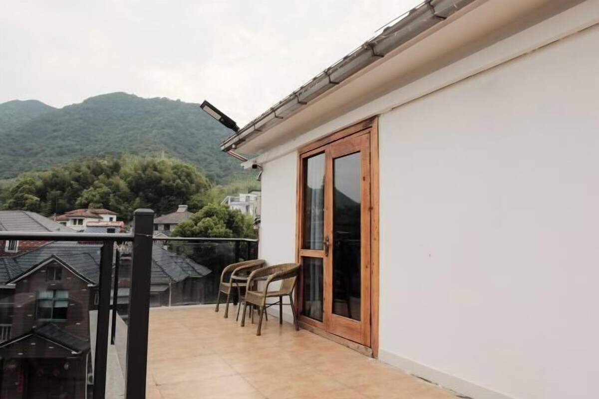 A balcony with a table and chairs, a sliding glass door, and a view of a mountain.