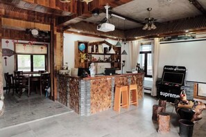 A rustic interior with a wooden bar area, a dining table, and a gaming console. - Yunshe Inn (Deqing)