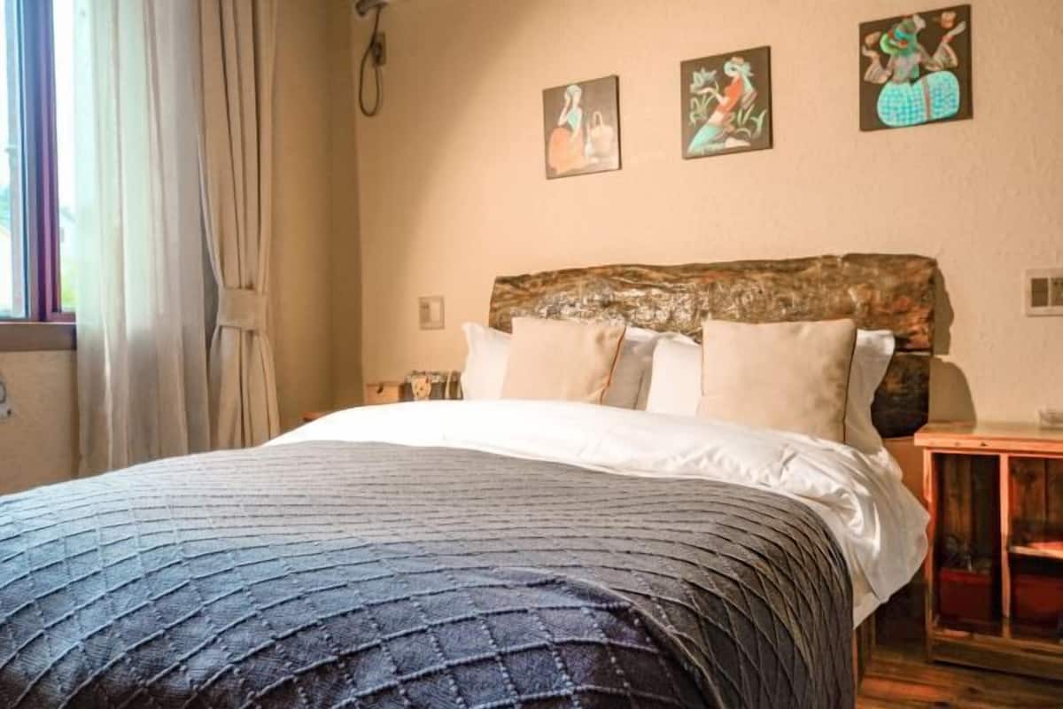 Un dormitorio con una cama, cabecera de madera y tres cuadros colgados en la pared.