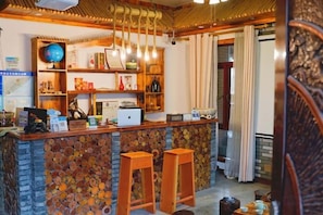 A bar area with a wooden counter, stools, and shelves with various items.