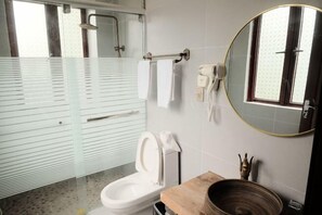 A bathroom with a toilet, a mirror, a towel rack, and a shower area. - Yunshe Inn (Deqing)