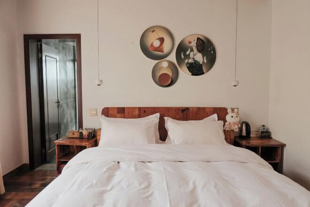 A bedroom with a wooden headboard, a bed with white bedding, two bedside tables with lamps, and three wall-mounted circular decorations.