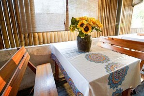 A table with a patterned tablecloth, a vase with sunflowers, and a wooden bench.