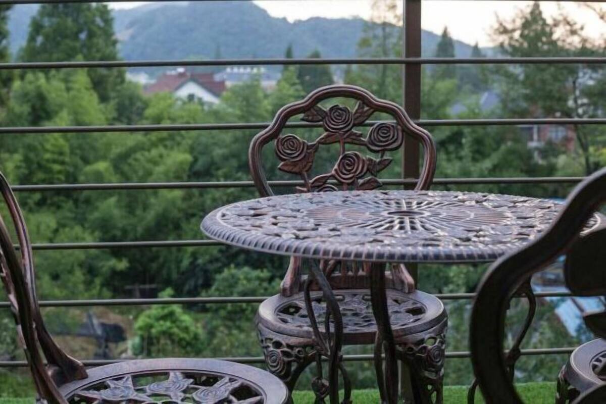 Juego de mesa y sillas de hierro forjado con diseños intrincados, ubicado en un balcón con vista a zonas verdes y edificios lejanos.