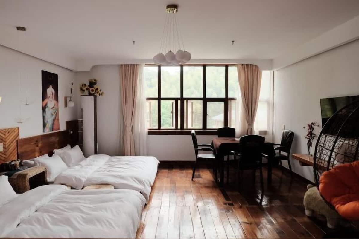 Una habitación con cama, escritorio y silla. Se observa una ventana con cortinas, una lámpara colgante y una estantería con objetos decorativos.