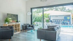 A modern living room with a pool area, featuring a large window, a flat-screen TV, and a sofa. - La Provence et ses cigales (Ceyreste)