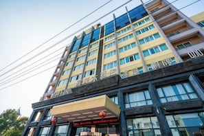A multi-story hotel building with a modern facade, large windows, and a prominent entrance. - Huilong Hotel (Tiantai County)