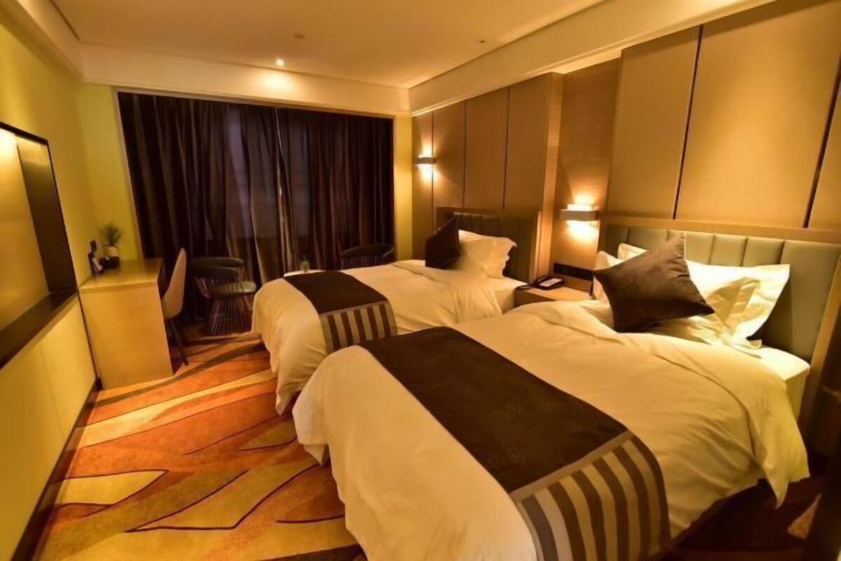 Une chambre d’hôtel avec deux lits, un bureau et une chaise.
