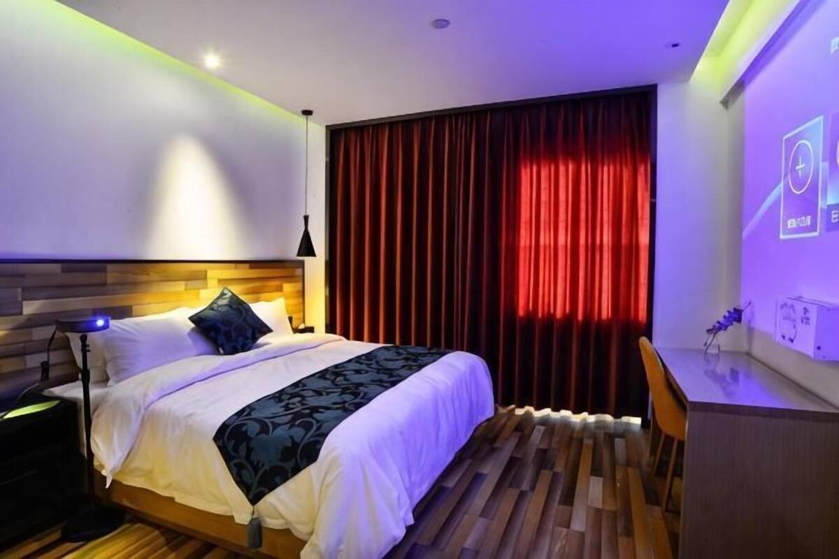 Une chambre à coucher avec un lit, un bureau et un projecteur fixé au mur.