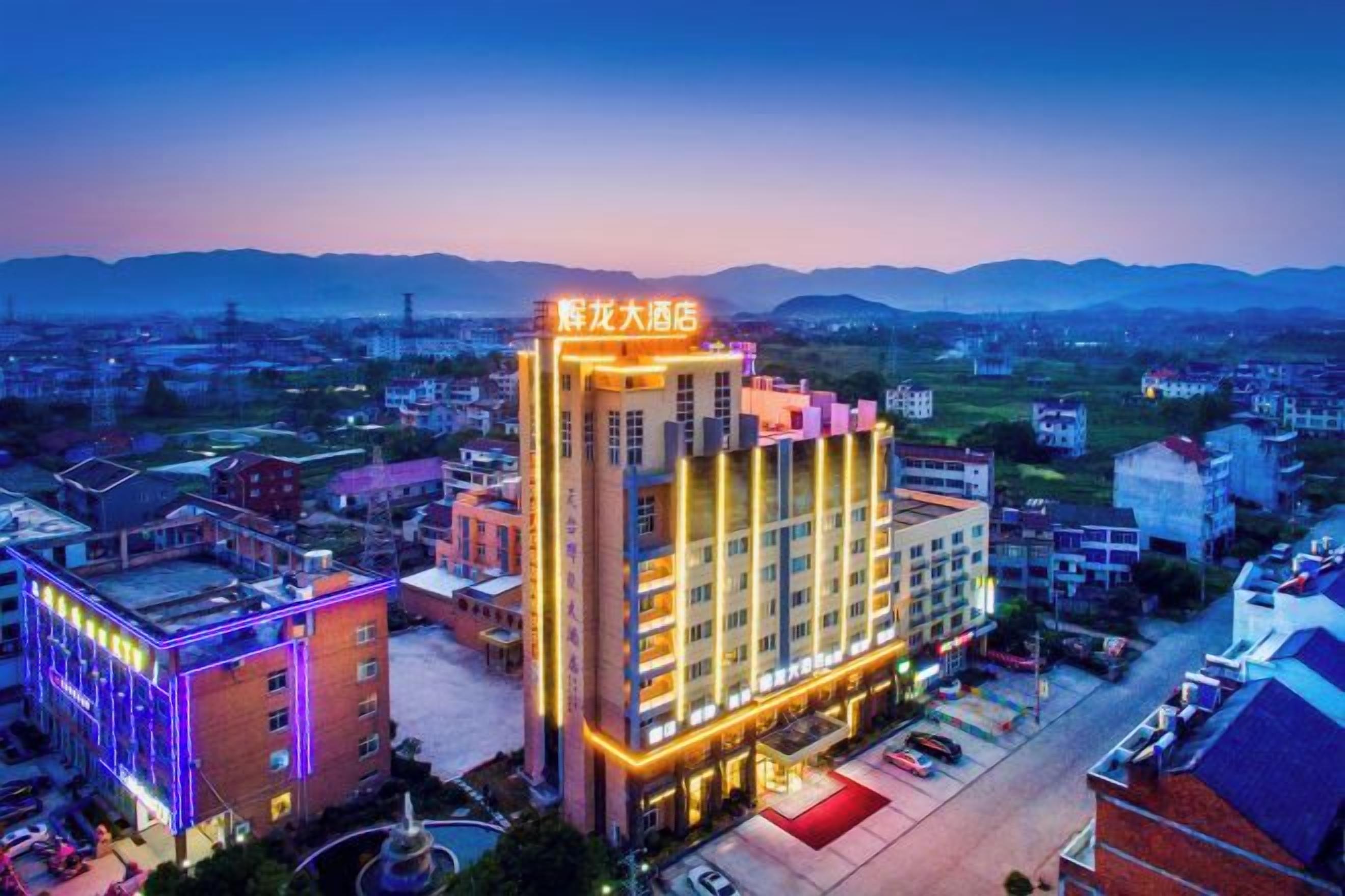 Un hotel de varios pisos con un letrero llamativo, rodeado de otros edificios y un cielo despejado.