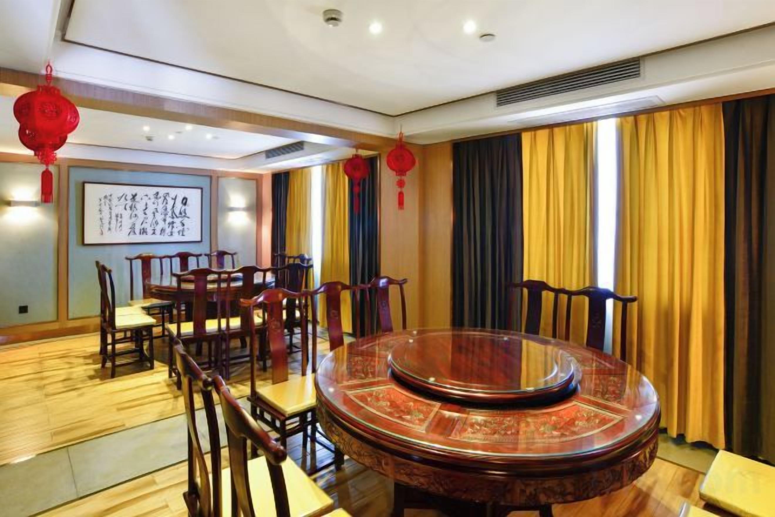 Un comedor chino tradicional con una mesa redonda, sillas de madera y farolillos rojos.