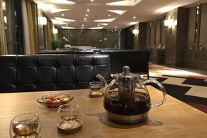 A dining table with a teapot, glasses, and a bowl of fruit in a modern hotel setting. - Huilong Hotel (Tiantai County)