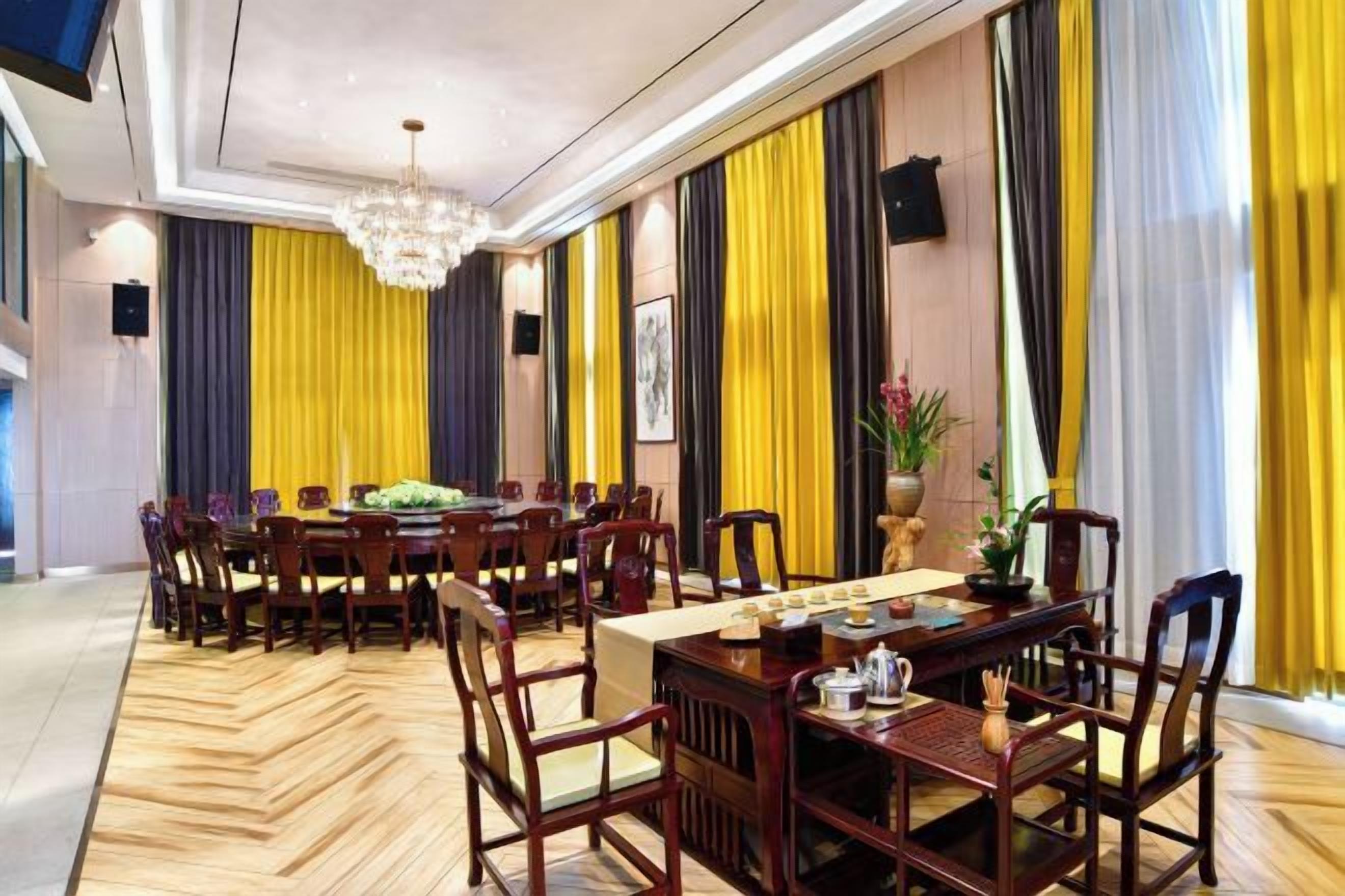 A dining area with a long table, multiple chairs, and a chandelier.