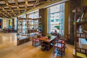 A spacious library with a wooden table and chairs, bookshelves, and large windows. - Huilong Hotel (Tiantai County)