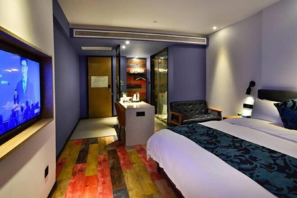 Une chambre d’hôtel comprenant un lit, un bureau, une chaise, une télévision et une salle de bain.