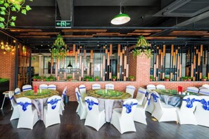 Un salón de conferencias con mesas redondas, sillas blancas y cintas azules.