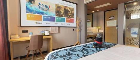 Una habitación de hotel con una cama, un escritorio, una silla, una televisión mostrando una película y un perro.
