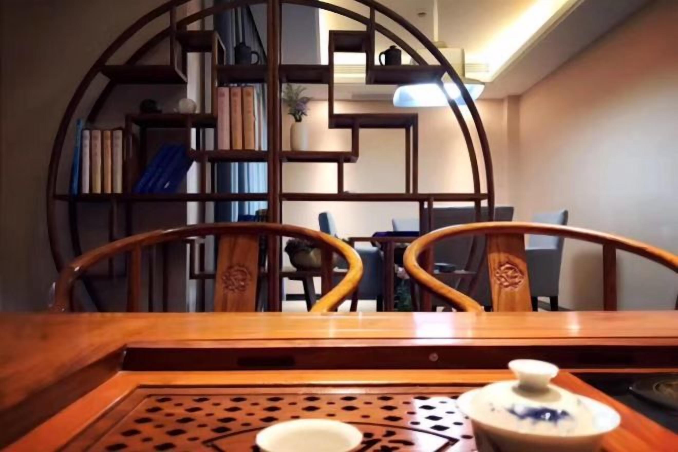 Un área de comedor con una mesa de madera, sillas y una estantería al fondo.