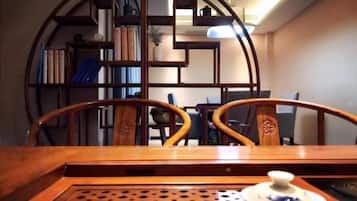 Un área de comedor con una mesa de madera, sillas y una estantería al fondo.