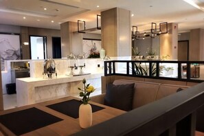 A modern kitchen with a marble countertop, a dining area with a sofa, and a balcony with a railing. - Huilong Hotel (Tiantai County)