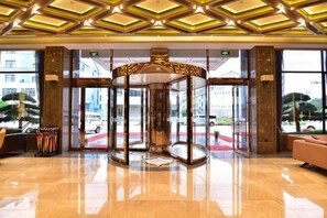 A lobby with a revolving door, large windows, and a red carpet.
