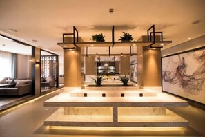 A modern lobby with a central marble staircase, a reception desk, and a large abstract painting on the wall. - Huilong Hotel (Tiantai County)