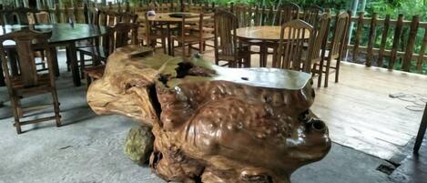 A rustic wooden table with a metal top, surrounded by wooden chairs in an outdoor setting.
