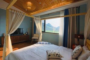 A bedroom with a bed, curtains, a television, and a view of the outdoors. - Black Valley Purple Rose Inn (Chongqing)