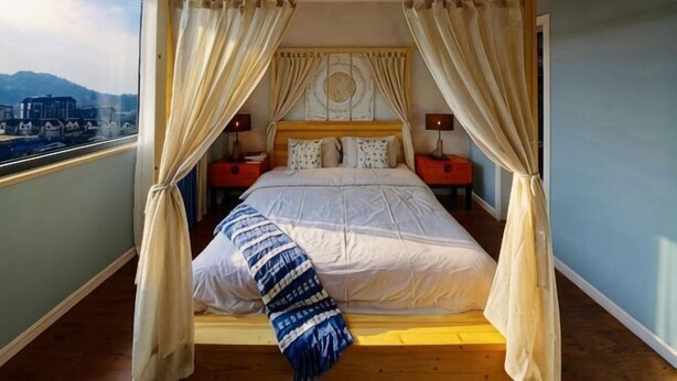 A bedroom with a canopy bed, a view of the city, and a wooden floor. - Black Valley Purple Rose Inn (Chongqing)