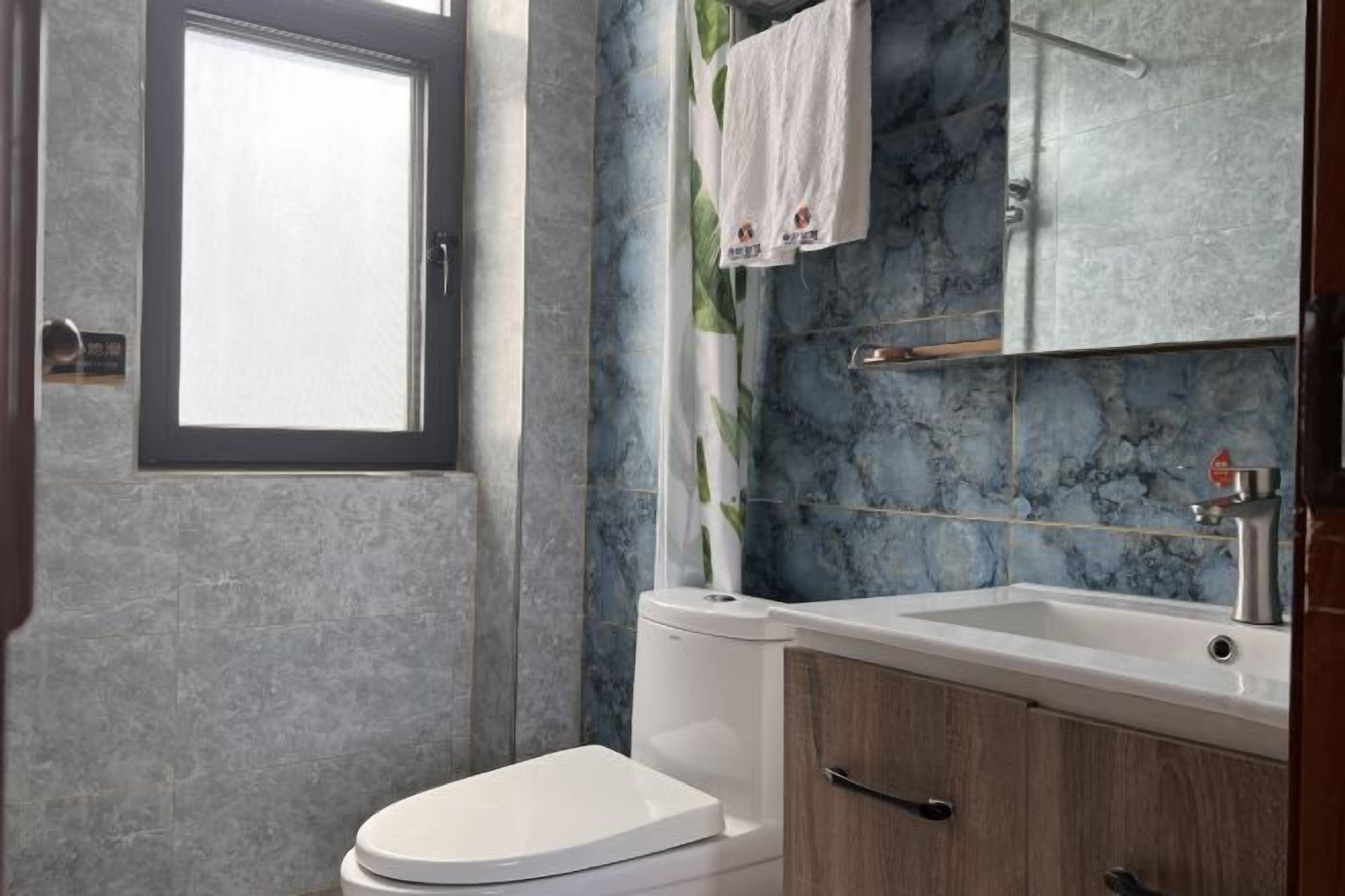 Een badkamer met toilet, wastafel en spiegel.