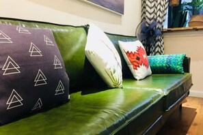 A green leather sofa with patterned cushions and a decorative fan. - Black Valley Purple Rose Inn (Chongqing)